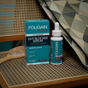 FOLIGAIN DHT Blocker Serum bottle and box on a woven chair seat.