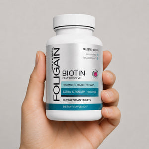 Hand holding a bottle of FOLIGAIN Biotin Fast Dissolve tablets.