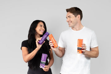 Woman and man holding purple and orange FOLIGAIN hair care bottles.