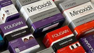 Assorted FOLIGAIN minoxidil and TRIOXIDIL hair care products in boxes.