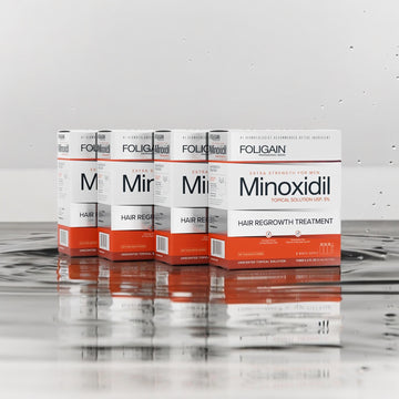 Boxes of FOLIGAIN Minoxidil 5% Topical Solution arranged on a reflective surface.