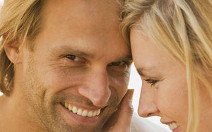 Smiling man and woman leaning their heads together.