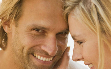 Smiling man and woman leaning their heads together.