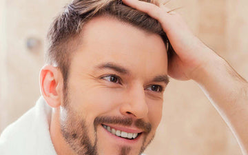 Smiling man running his hand through his short hair.