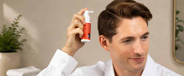 Man holding a FOLIGAIN TRIOXIDIL spray applicator beside his hair.