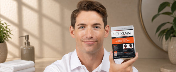 Man holding FOLIGAIN Advanced Hair Regrowth Treatment with 5% minoxidil and 5% TRIOXIDIL.